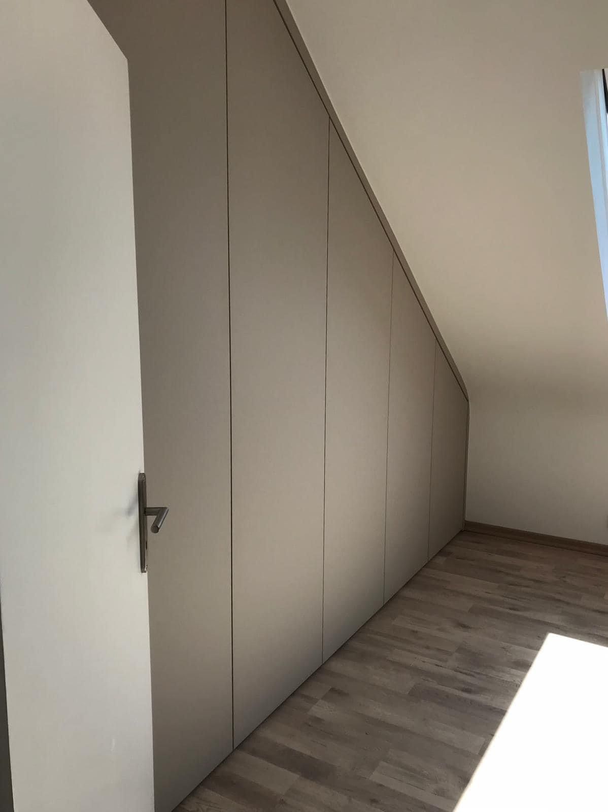 In einem Raum mit Dachschräge steht eine Tür offen.