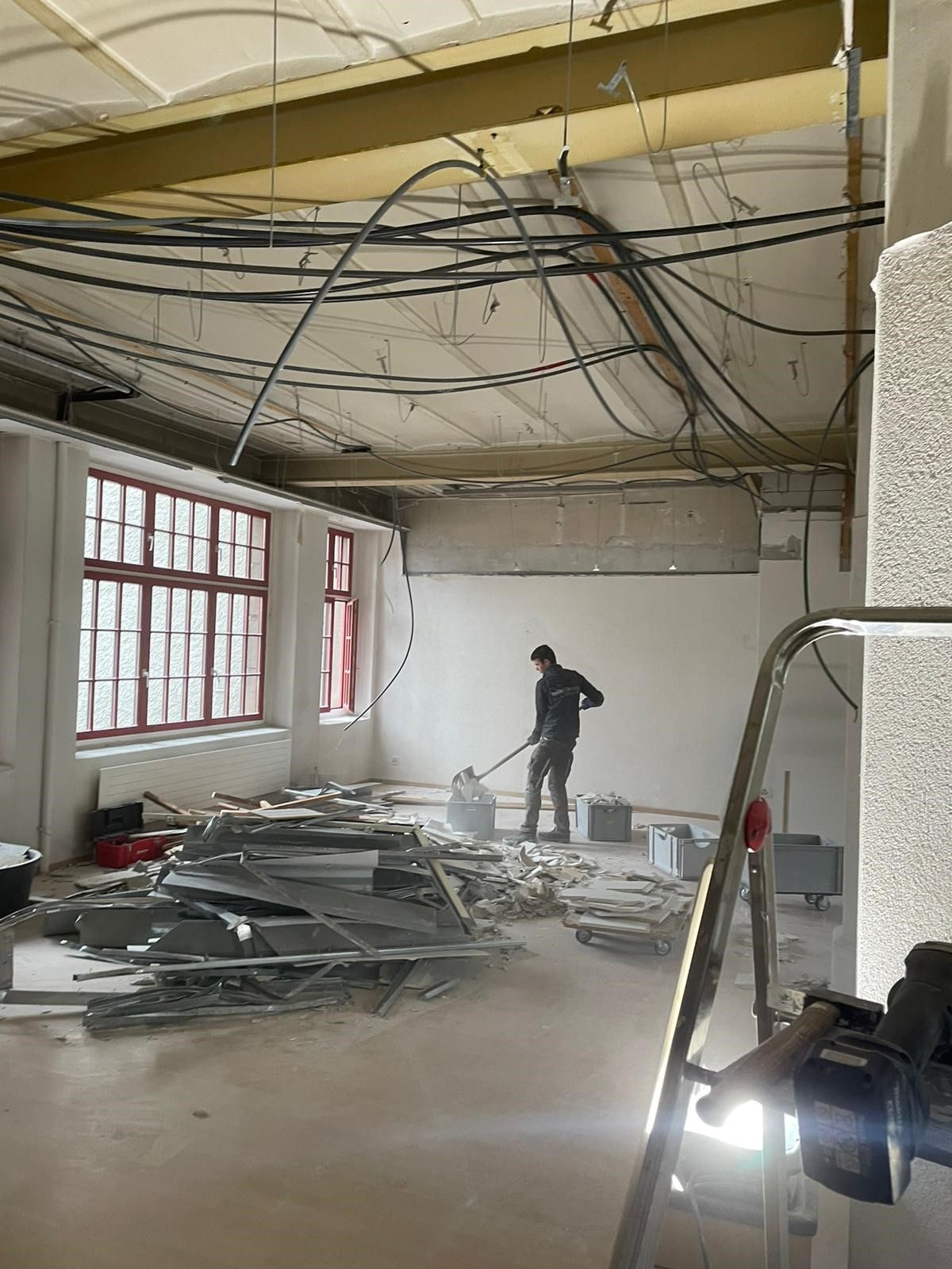 Ein Mann steht mit einem Staubsauger in einem leeren Raum.