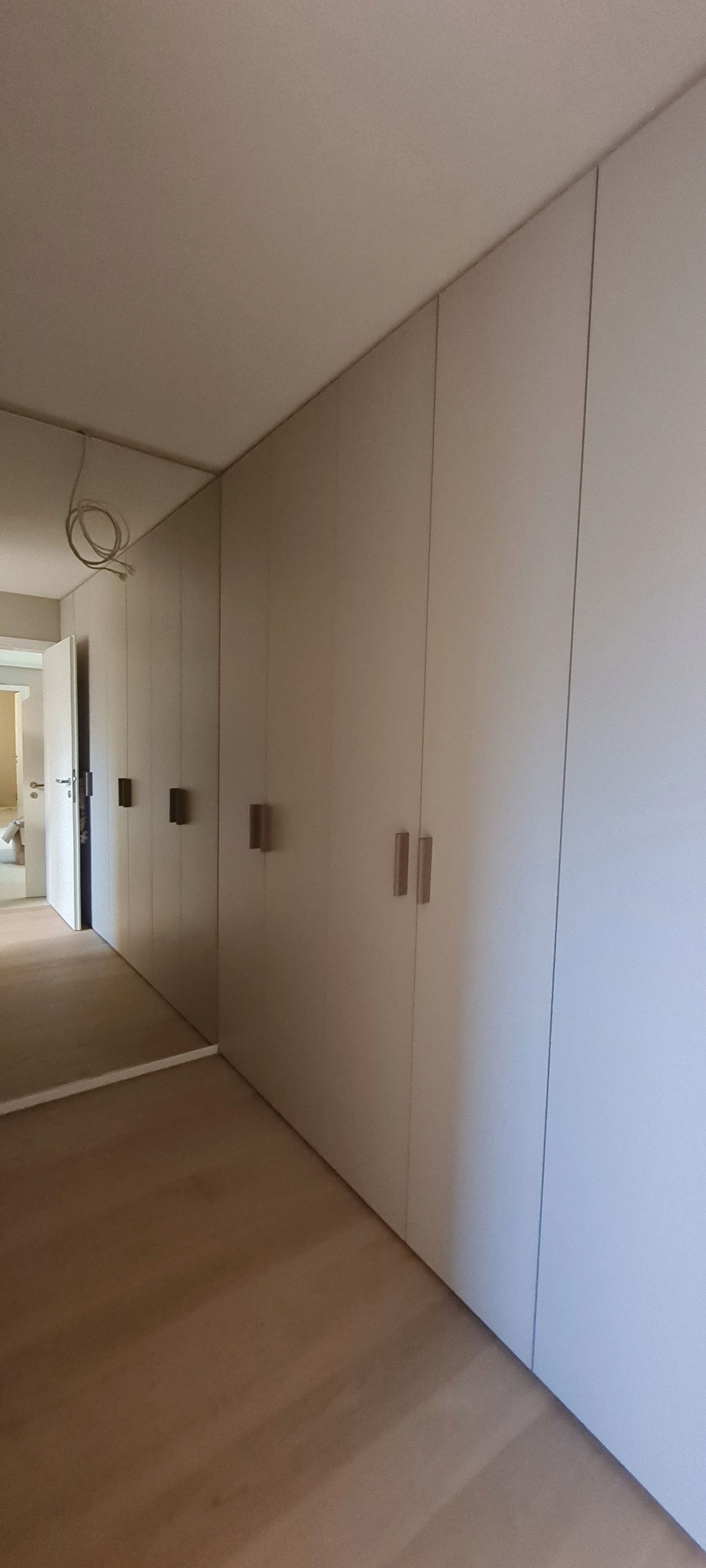 Ein Flur mit weißen Schränken und einem großen Spiegel an der Wand.