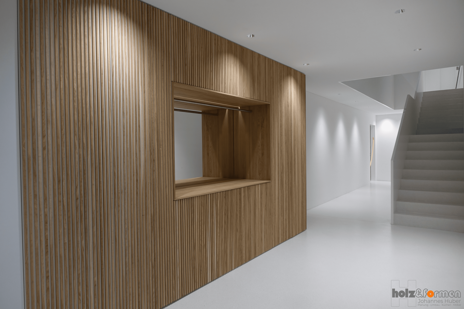 Ein Flur mit einer Holzwand und einer Treppe im Hintergrund.
