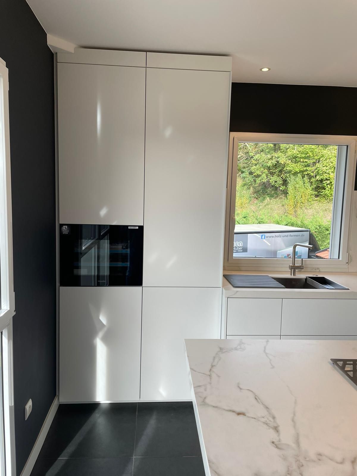 Eine Küche mit weißen Schränken und einer Marmorarbeitsplatte