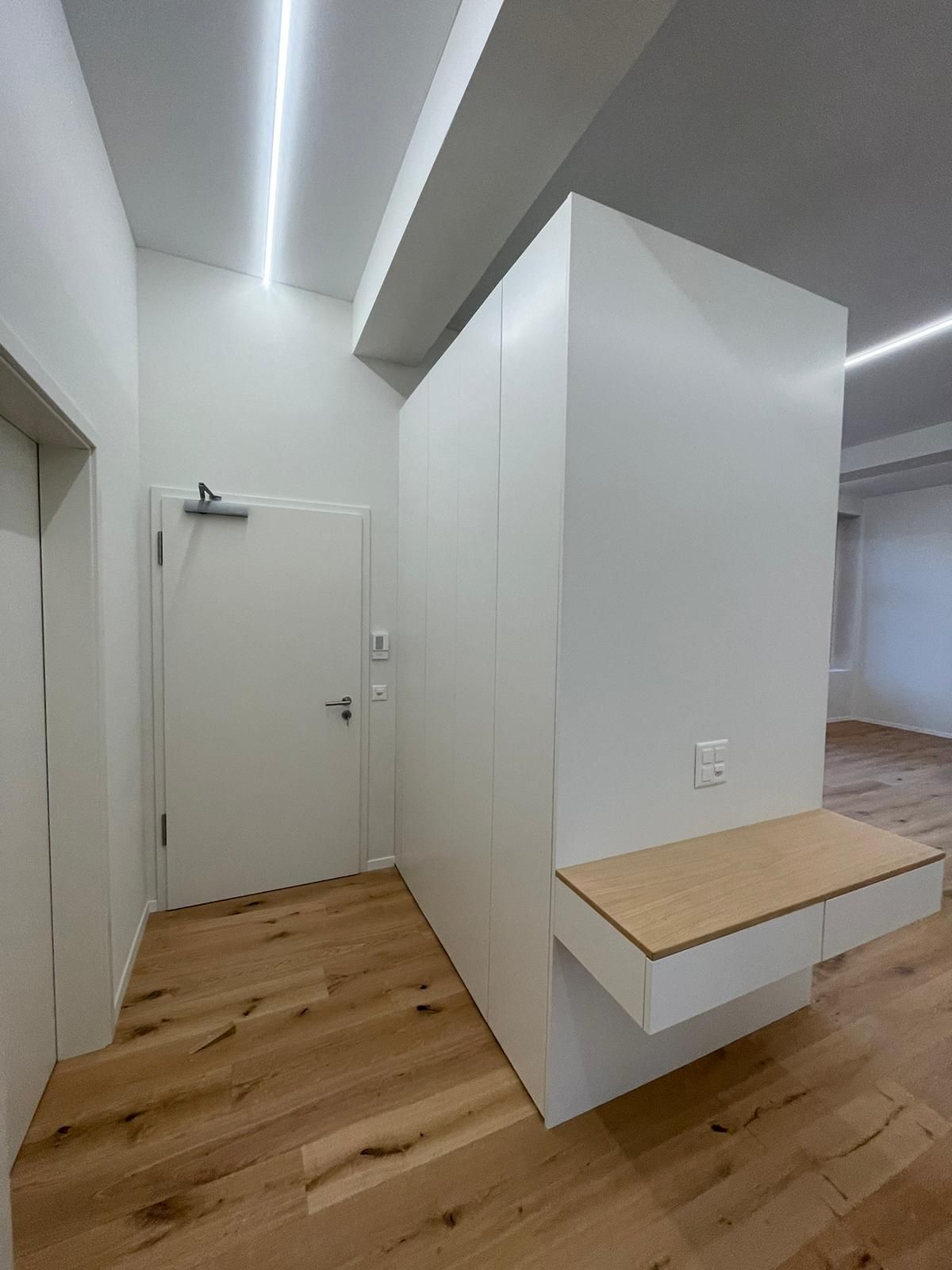 Ein Flur mit Holzboden und weißen Wänden