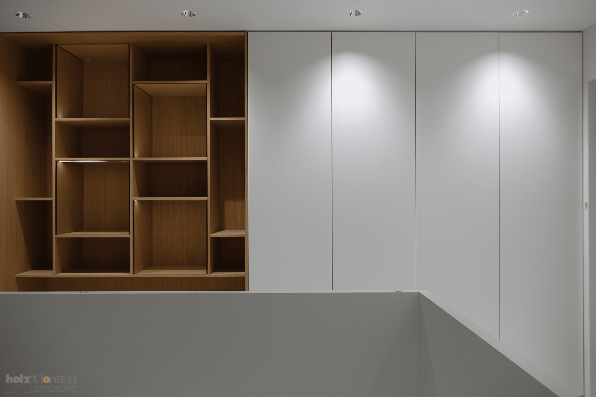 Eine weiße Wand mit Holzregalen und weißen Schränken.