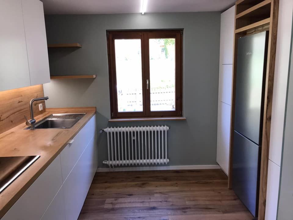 Eine Küche mit Spüle, Kühlschrank und Fenster