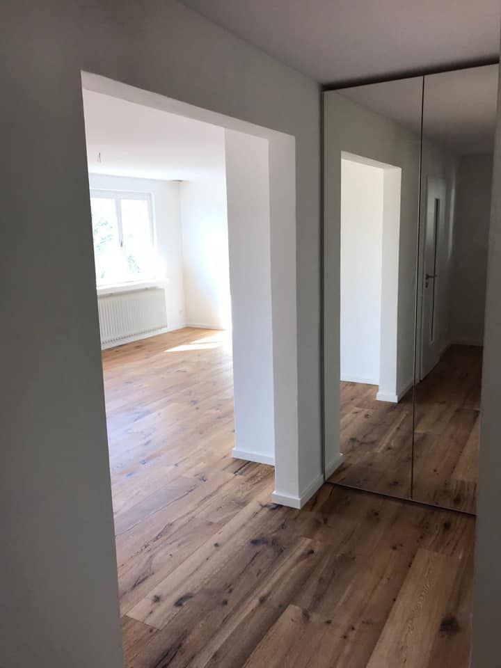 Ein Flur mit Hartholzböden und einem großen Spiegel.