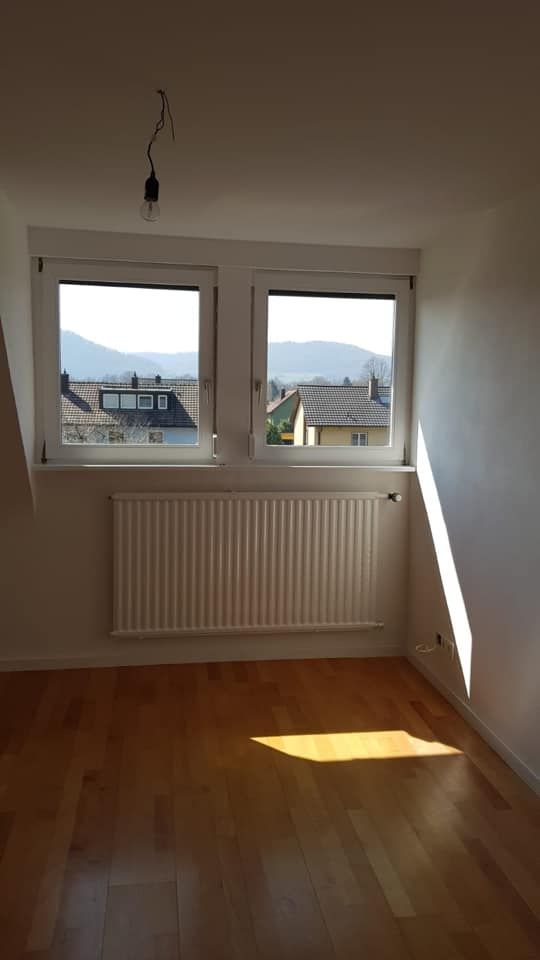Ein leerer Raum mit zwei Fenstern und einem Heizkörper.