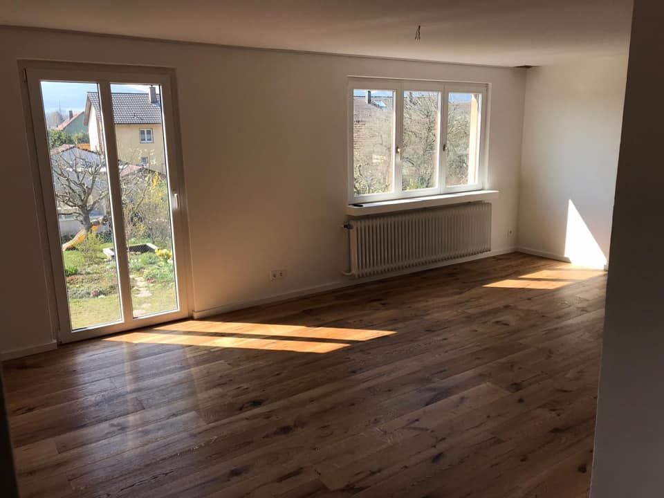 Ein leerer Raum mit Hartholzböden und Glasschiebetüren