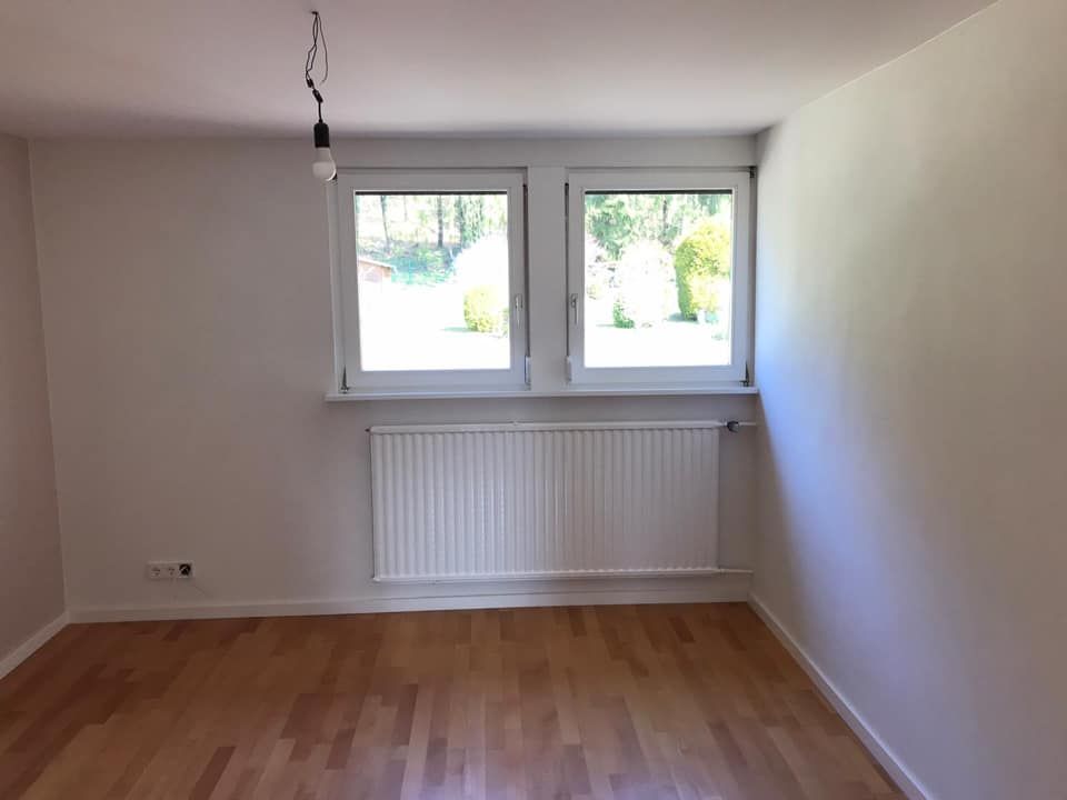 Ein leerer Raum mit zwei Fenstern und einem Heizkörper