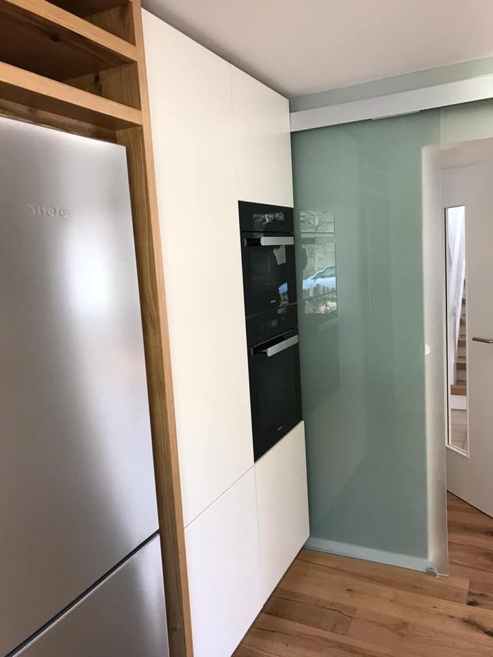 Eine Küche mit Kühlschrank, Backofen und Glasschiebetür.