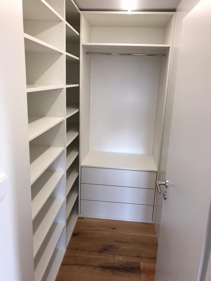 Ein begehbarer Kleiderschrank mit vielen Regalen und Schubladen