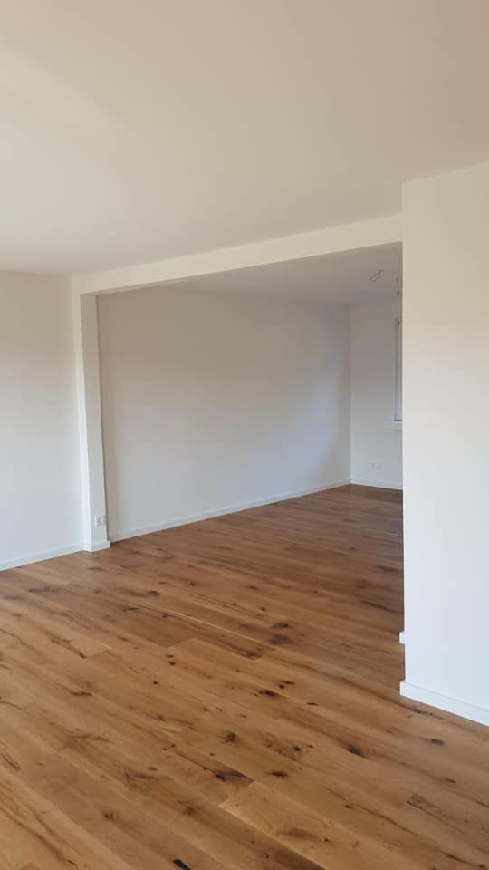 Ein leeres Wohnzimmer mit Hartholzböden und weißen Wänden.