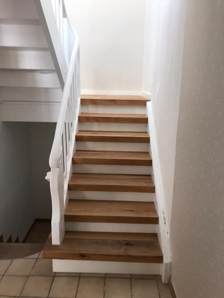 Eine Holztreppe mit einem weißen Geländer in einem Raum.