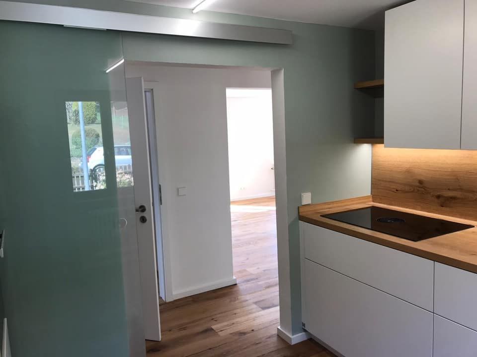 Eine Küche mit weißen Schränken, Holzarbeitsplatten und einem Herd mit Backofen.