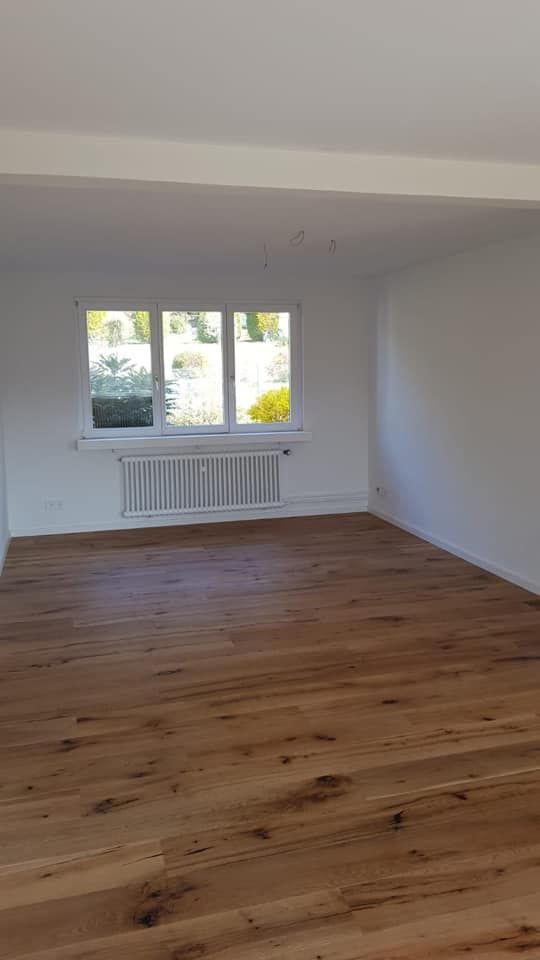 Ein leeres Wohnzimmer mit Hartholzböden und einem Fenster.