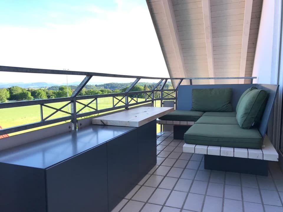 Ein Balkon mit Couch und Tisch mit Blick auf ein Feld