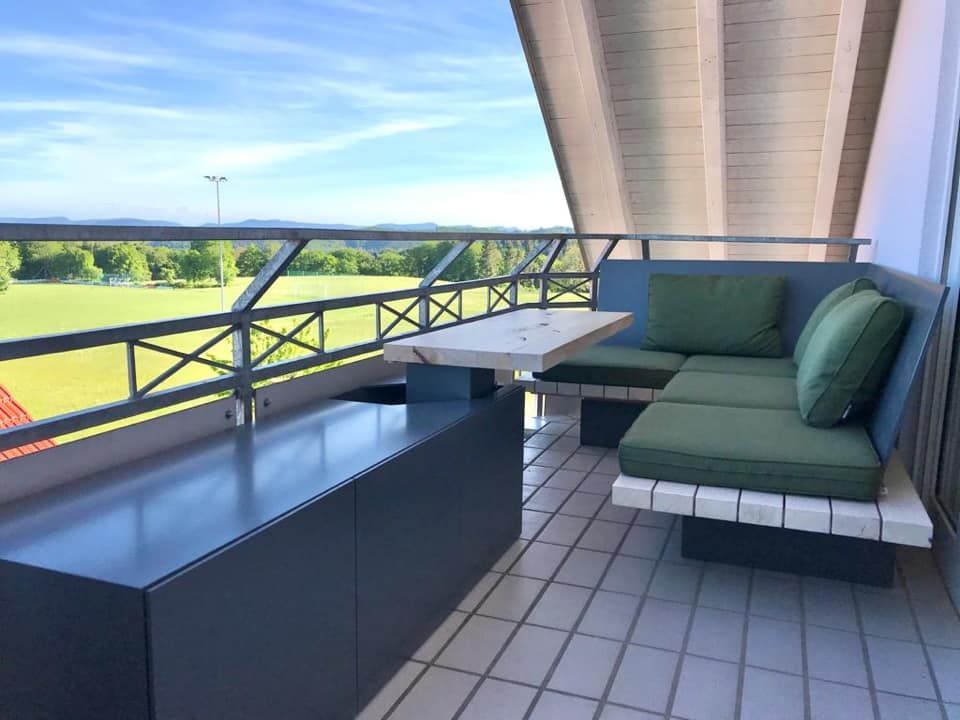 Ein Balkon mit Couch und Tisch mit Blick auf ein Feld.