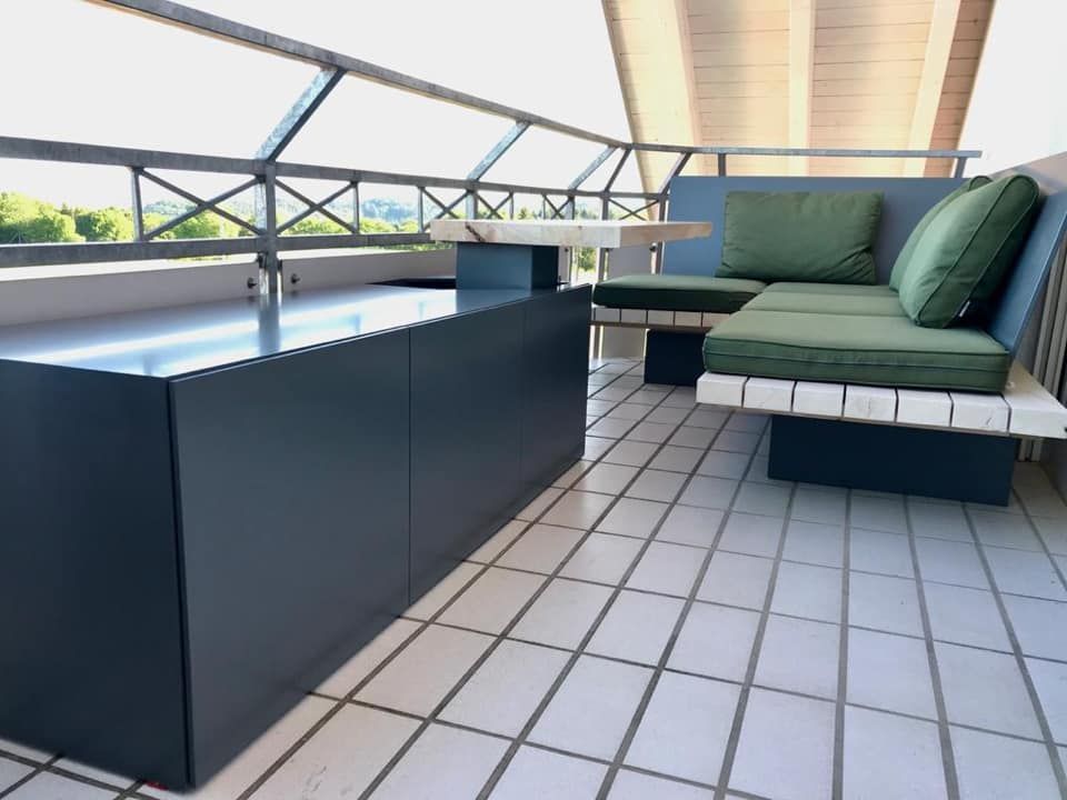 Ein Balkon mit einer Couch und einem Tisch mit grünen Kissen