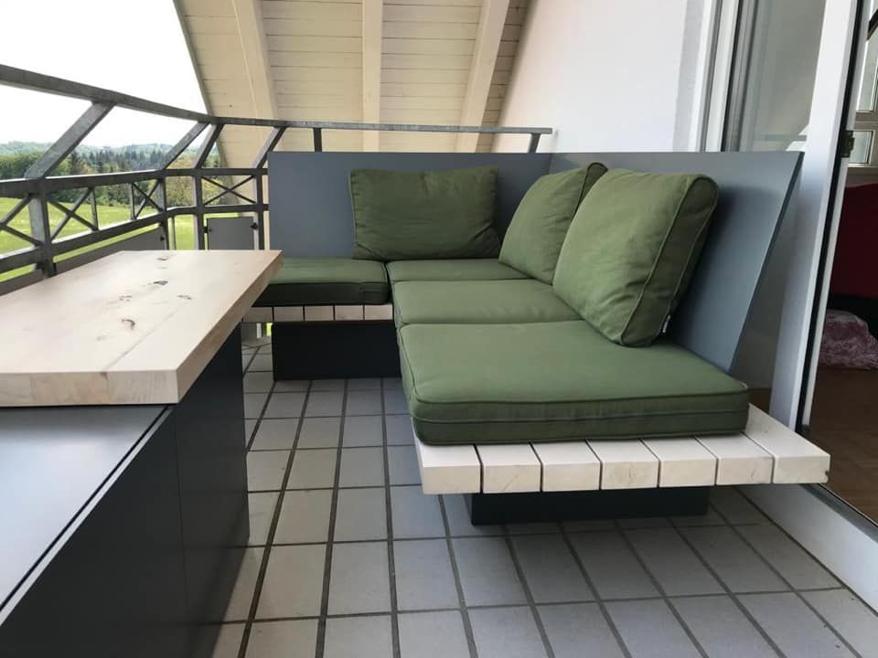 Ein Balkon mit einer Couch und einer Bank mit grünen Kissen