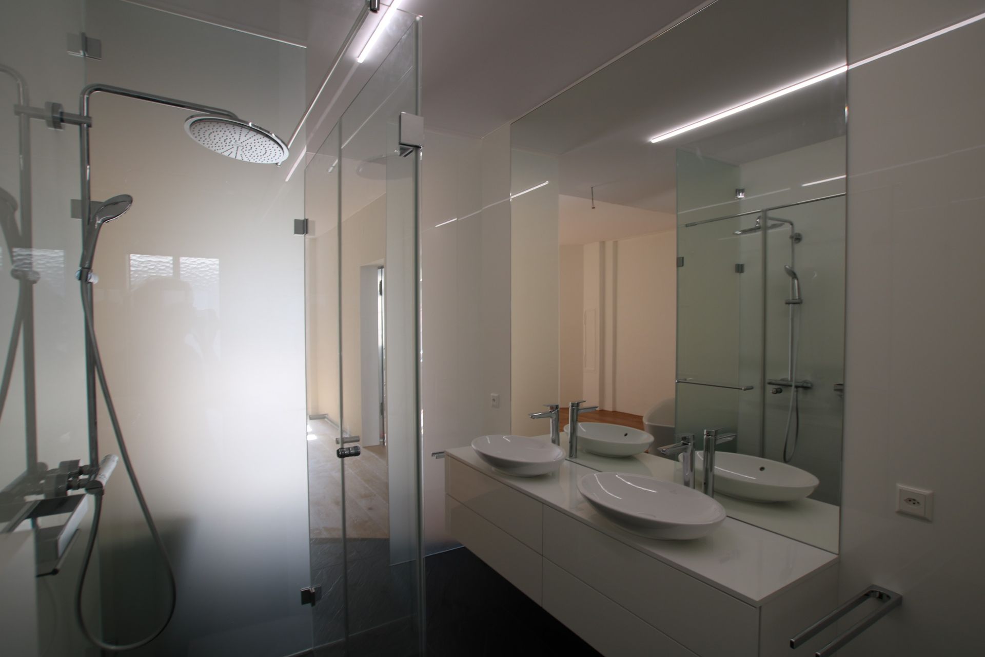 Ein Badezimmer mit zwei Waschbecken, einer Dusche und einem Spiegel.