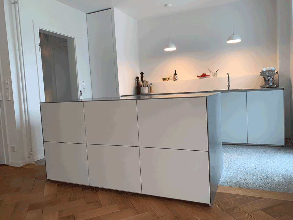 Eine Küche mit weißen Schränken und einer großen Insel in der Mitte.