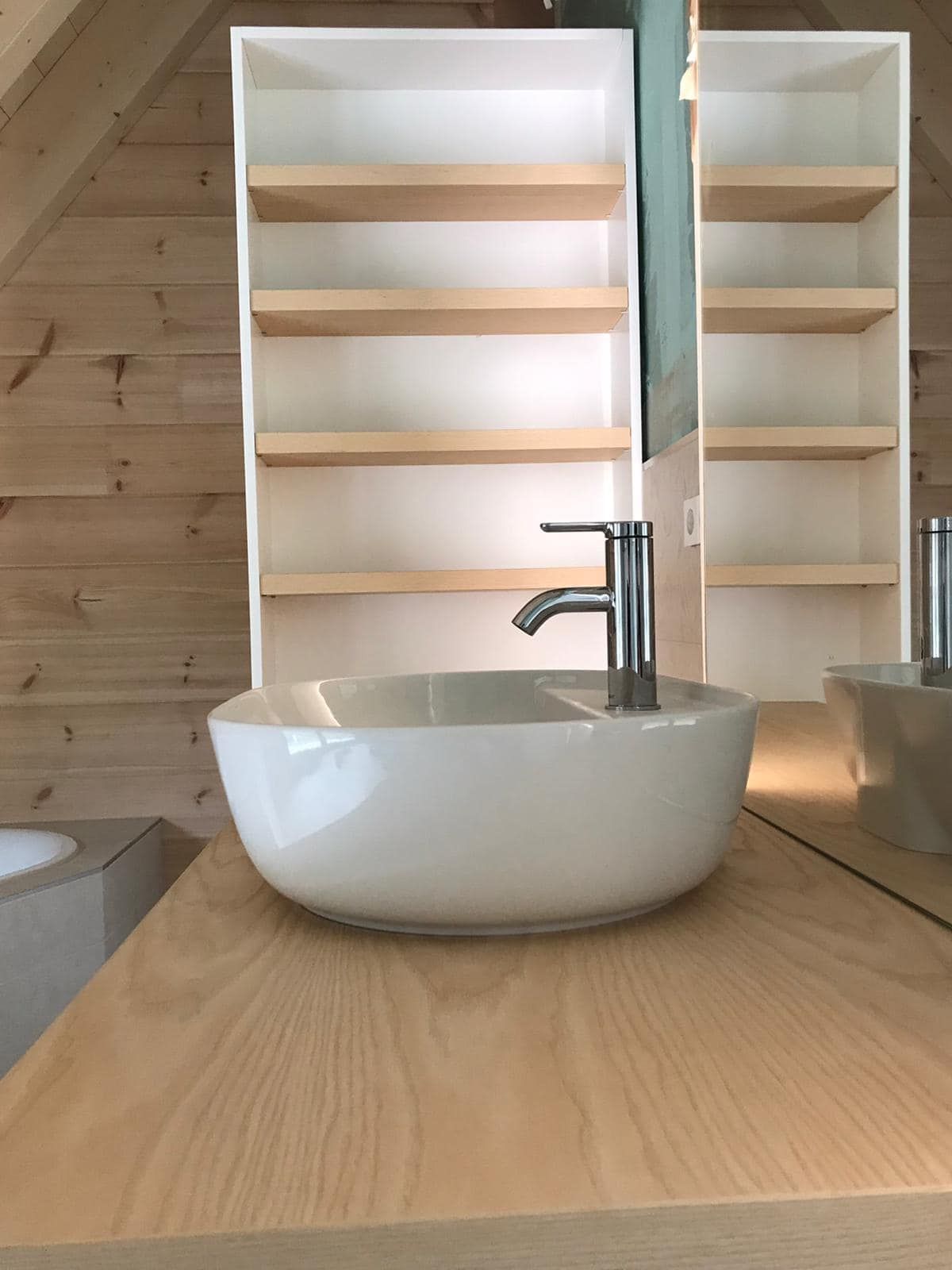 Ein Badezimmer mit Waschbecken, Spiegel und Regalen