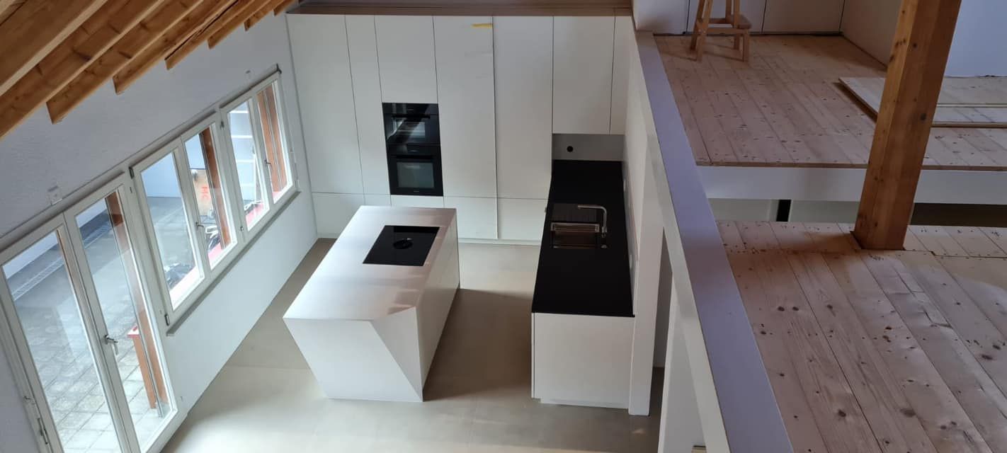 Eine Luftaufnahme einer Küche mit weißen Schränken und schwarzen Arbeitsplatten.