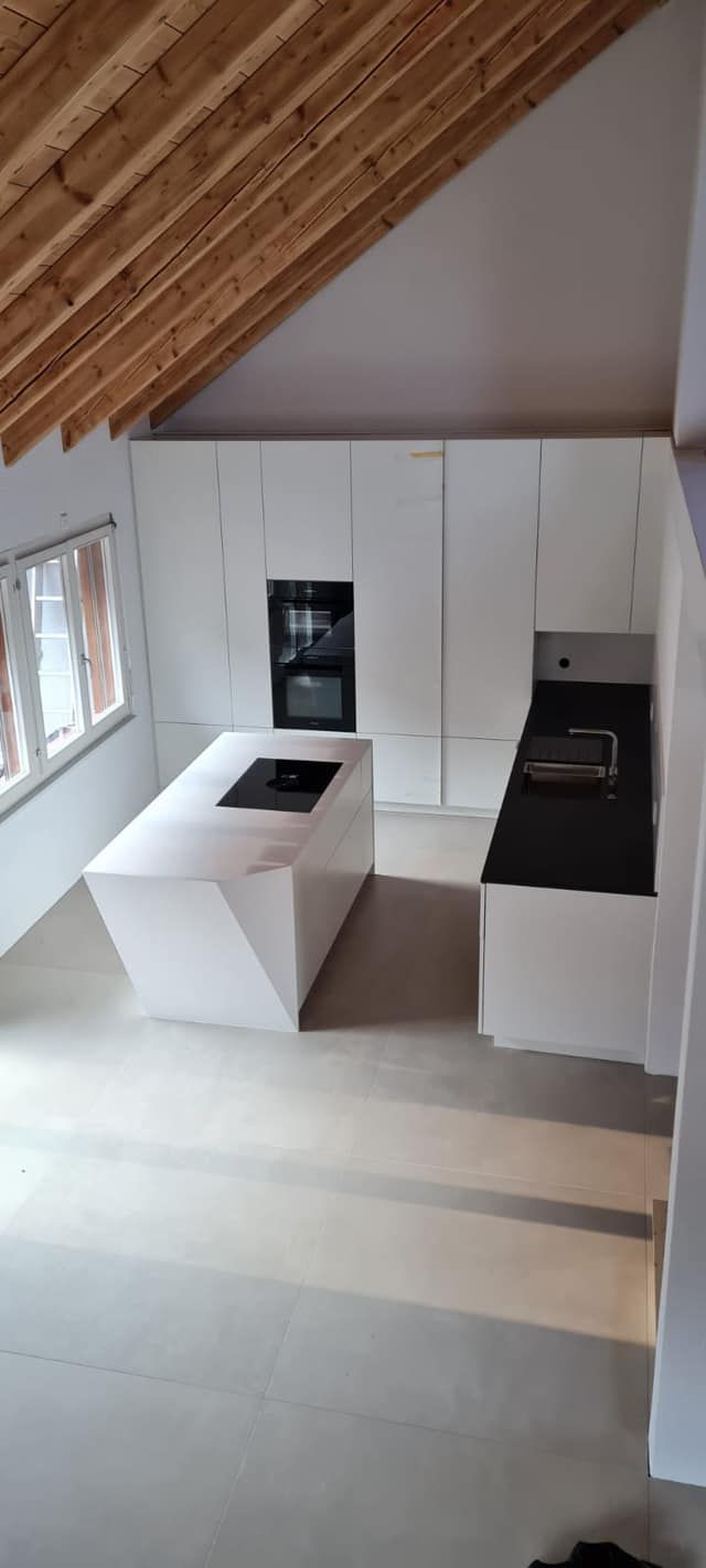 Eine Küche mit weißen Schränken und einer schwarzen Arbeitsplatte.