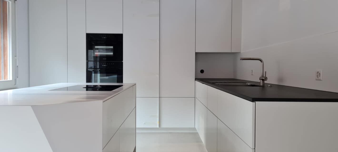 Eine Küche mit weißen Schränken und einer schwarzen Arbeitsplatte.
