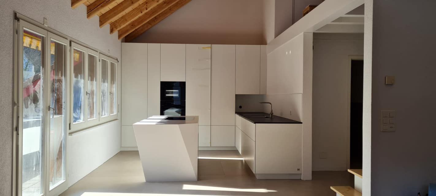 Eine Küche mit weißen Schränken und einer Holzdecke.