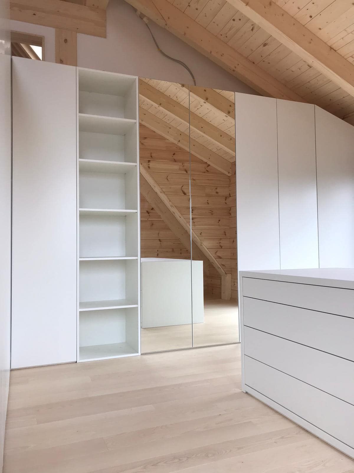 Ein Raum mit Holzdecke und weißen Regalen