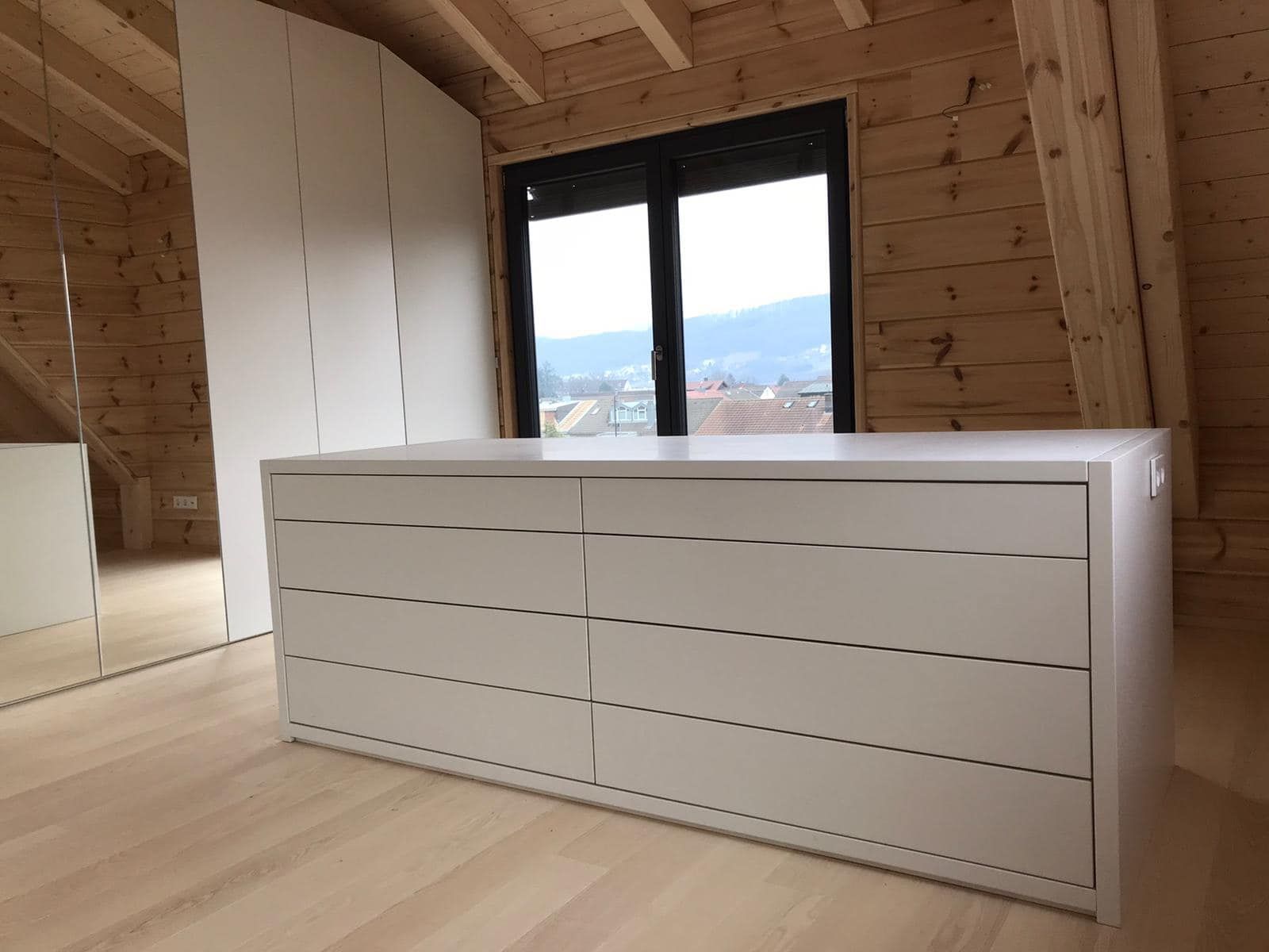 Ein Holzzimmer mit einer Kommode und einem Fenster