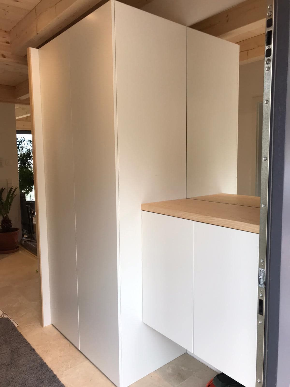 Ein weißer Schrank mit einer Holzplatte und einem Spiegel in einem Zimmer.