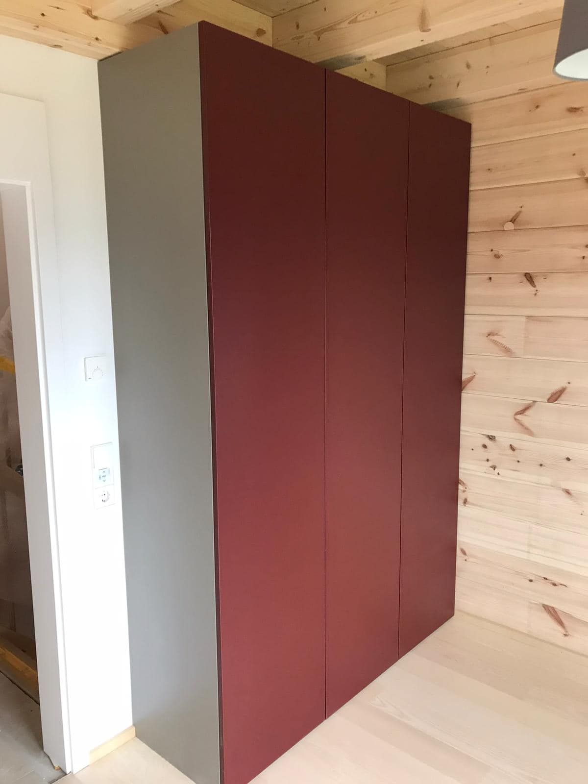 Ein rot-grauer Kleiderschrank in einem Holzzimmer.