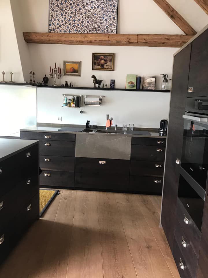 Eine Küche mit schwarzen Schränken und einer Edelstahlspüle