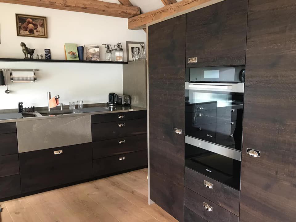 Eine Küche mit Holzschränken und einem Edelstahlofen