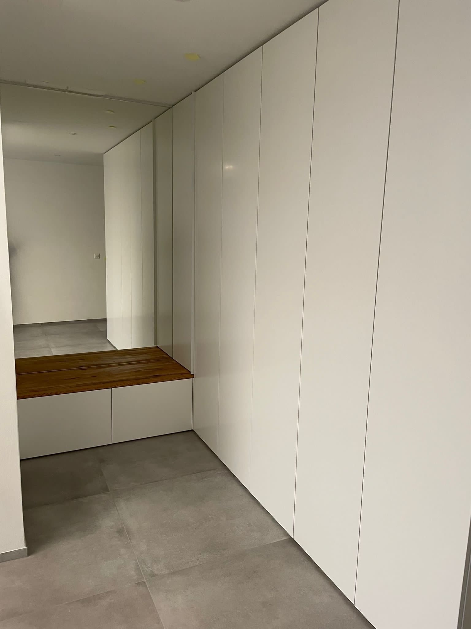 Ein Flur mit weißen Wänden und einem Spiegel an der Wand.