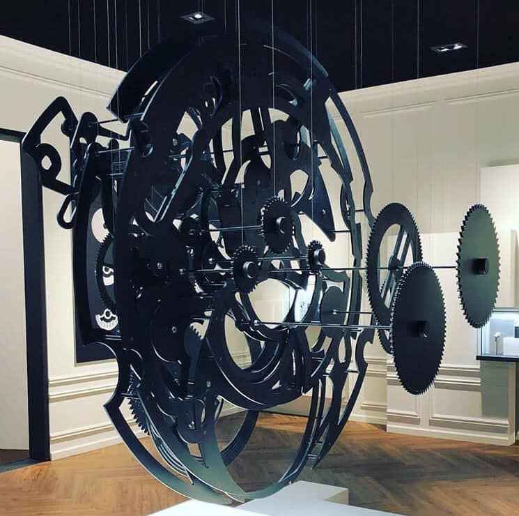 Eine große schwarze Skulptur hängt von der Decke in einem Raum