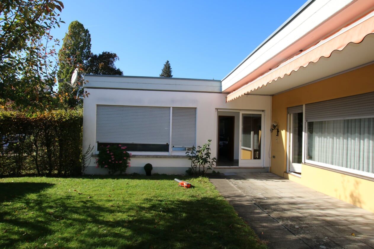 Ein weißes Haus mit einer rosa Markise auf dem Dach