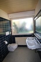 Ein Badezimmer mit Toilette, Waschbecken und Fenster.