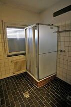 Ein Badezimmer mit Duschkabine und Fenster.