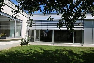 Ein Haus mit vielen Fenstern und einem Baum davor.