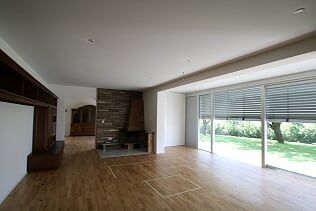 Ein leeres Wohnzimmer mit Hartholzböden, einem Kamin und Glasschiebetüren.