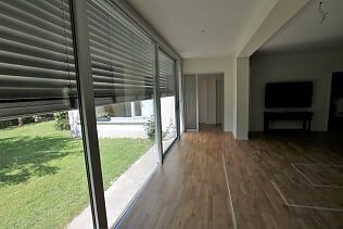 Ein Wohnzimmer mit vielen Fenstern und Jalousien.