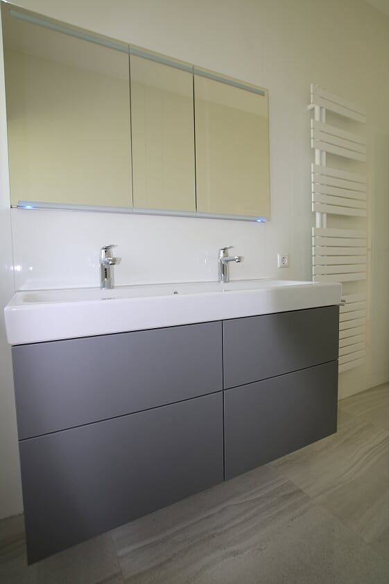 Ein Badezimmer mit zwei Waschbecken, einem Spiegel und einem Handtuchhalter.