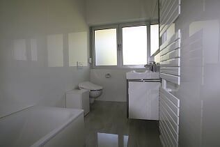 Ein Badezimmer mit Badewanne, Waschbecken, Toilette und Fenster.