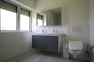 Ein Badezimmer mit Toilette, Waschbecken, Spiegel und Fenster.