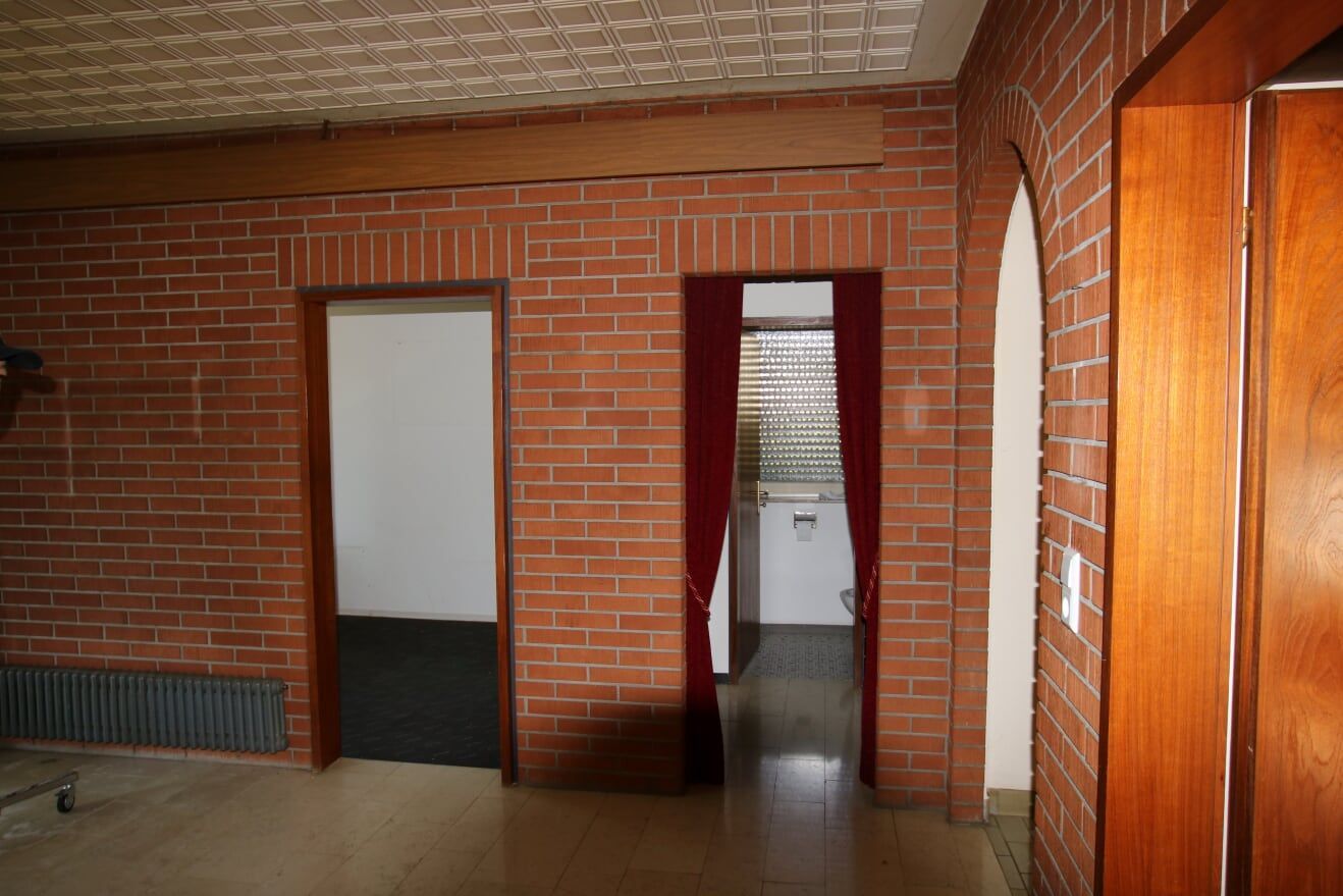 Ein Flur mit Backsteinwänden und Holztüren, der zu einer Küche führt.