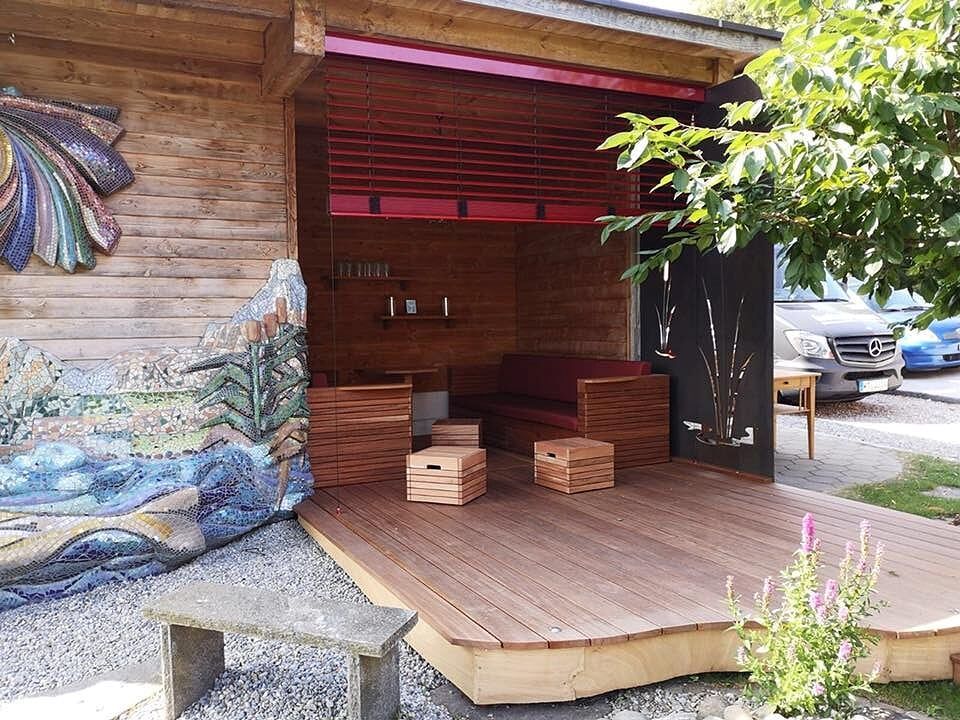 Ein Holzhaus mit einer Holzterrasse und einem Gemälde an der Wand.