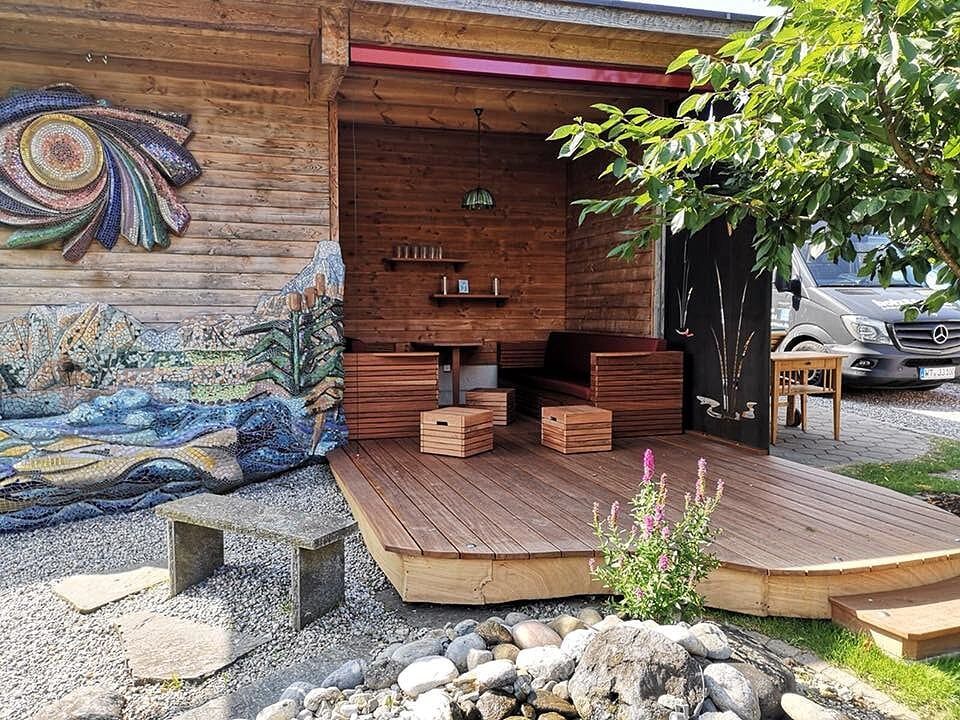 Ein Holzhaus mit einer Holzterrasse und einem Gemälde an der Wand.