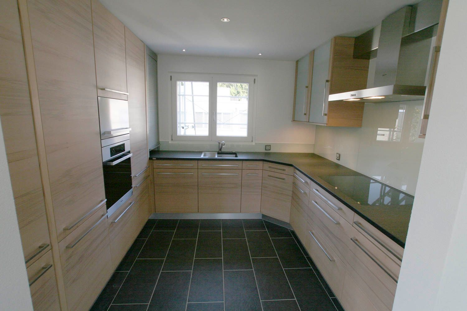 Eine Küche mit Holzschränken und schwarzen Arbeitsplatten